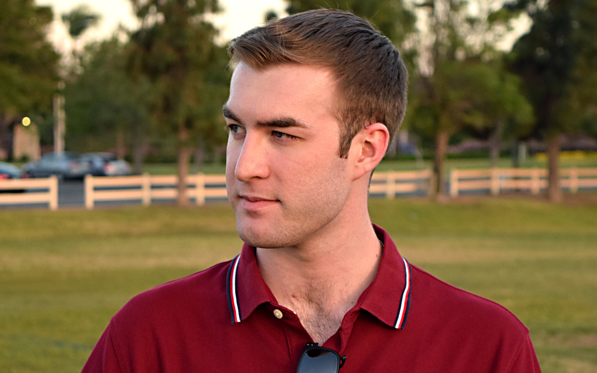 Headshot of Evan Harr standing in a grassy field with a white fence behind him.